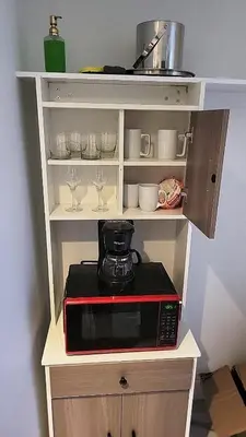 a microwave in a shelf with cups and glasses at The Royal Studio of Beachwalk in Hallandale Beach