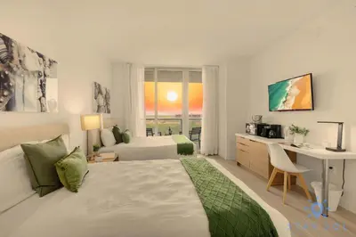 a white bedroom with a bed and a desk and a desk at Studio Miami Views - Amenities in Hallandale Beach