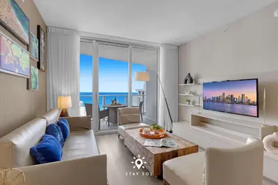 a living room with a couch and a tv at Ocean Views - Balcony & Resort Pool Paradise in Hollywood