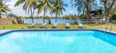 a swimming pool with chairs and a body of water at The Miami Enchanted Lake House in Ojus