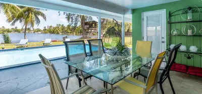 a dining room with a glass table and chairs and a pool at The Miami Enchanted Lake House in Ojus