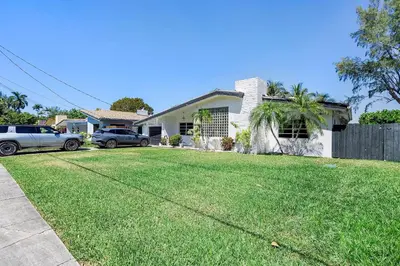 a house with two cars parked in a yard at The Miami Enchanted Lake House in Ojus