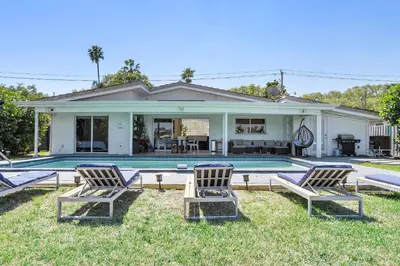 a house with a pool and two chairs in the yard at The Miami Enchanted Lake House in Ojus