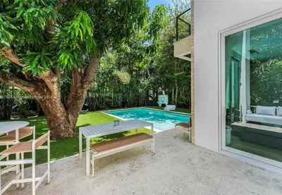 a patio with a table and chairs next to a pool at Villa Tranquil Luxe Modern Oasis with Private Pool in Miami Beach in Miami Beach