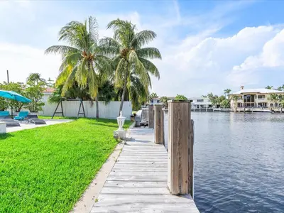 a dock with palm trees next to a body of water at luxury house by the water in Eastern Shores