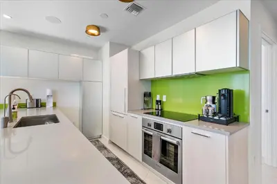 a kitchen with white cabinets and a green wall at POSH Ocean View Penthouse - Heated Pool, Gym, Office! 10mins Beach in Miami