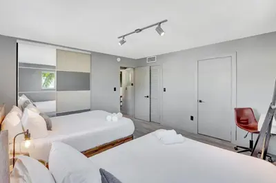 a bedroom with two beds and a red chair at Newly Renovated 1BR Condo Near South Beach in Miami Beach