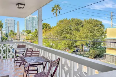a balcony with tables and chairs and palm trees at Newly Renovated 1BR Condo Near South Beach in Miami Beach
