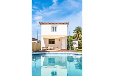 a villa with a swimming pool in front of a house at Lux 6BR Villa with Pool, King Beds and Top Amenities in Miami