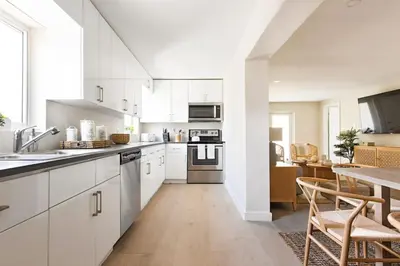 a kitchen with white cabinets and a table with chairs at Lux 6BR Villa with Pool, King Beds and Top Amenities in Miami
