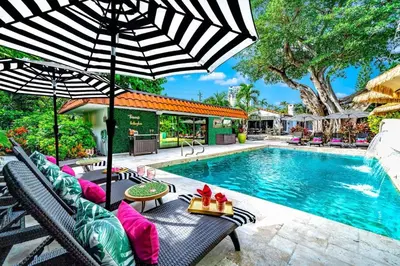 a pool with chairs and an umbrella next to a swimming pool at Beach Estate Las Olas Beach Best Location in Fort Lauderdale