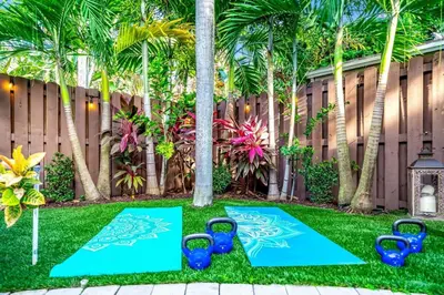 a garden with blue chairs and palm trees at 5BR Luxury Mins to Las Olas, Shops and Beach in Fort Lauderdale