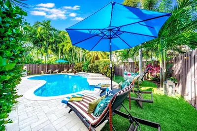 a patio with a blue umbrella next to a swimming pool at 5BR Luxury Mins to Las Olas, Shops and Beach in Fort Lauderdale
