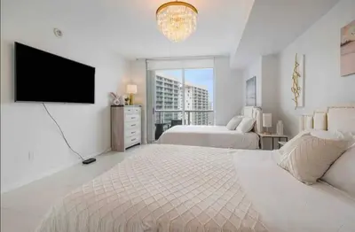 a white bedroom with two beds and a flat screen tv at Icon Brickell Amazing Ocean View in Miami