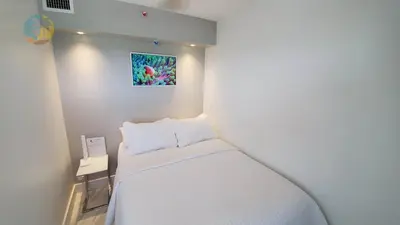 a small bedroom with a white bed and a painting on the wall at Alexander 1001 in Miami Beach