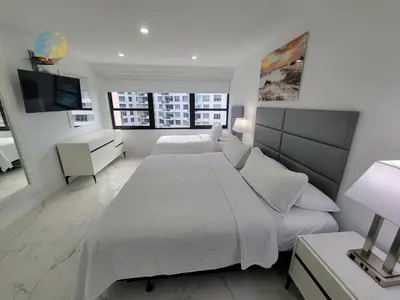 a white bedroom with a large bed and a television at Alexander 1115 in Miami Beach