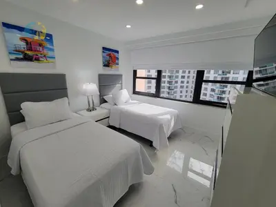 a white bedroom with two beds and a window at Alexander 1115 in Miami Beach
