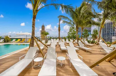 a row of white lounge chairs next to a pool at Luxury Downtown 2-BD Condo with beautiful city views in Miami