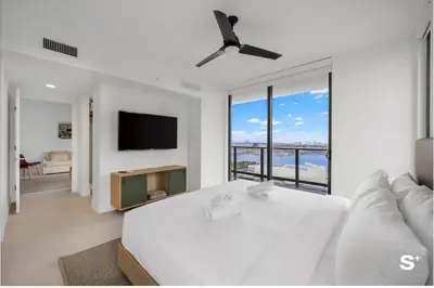 a white bedroom with a bed and a flat screen tv at Upscale 3-BD Condo in Downtown Miami in Miami