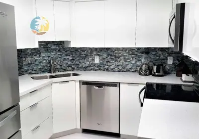 a white kitchen with white cabinets and a sink at Alexander 518 in Miami Beach