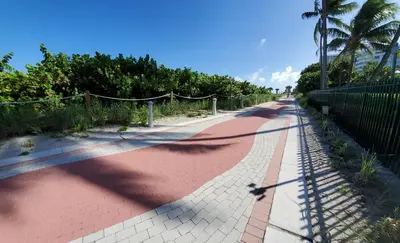 a red brick road with a fence and palm trees at Alexander 611 in Miami Beach