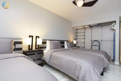 two beds in a bedroom with two lamps on the wall at Alexander 718 in Miami Beach