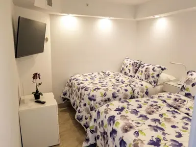 a bedroom with two beds and a tv on the wall at Alexander 802 in Miami Beach