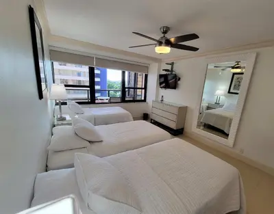 a white bedroom with two beds and a mirror at Alexander 819 in Miami Beach