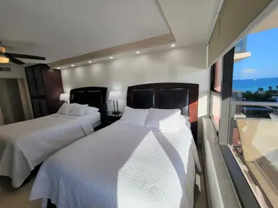 two beds in a room with a large window at Alexander 81921 in Miami Beach