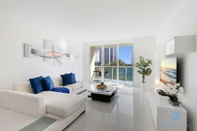 a white living room with a white couch and blue pillows at Apartment 2BR 2BTH - Free Parking in Sunny Isles Beach
