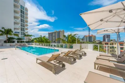 a swimming pool with chaise lounge chairs and an umbrella at Tiffany Tides - Resort-Style Beach Townhome - Gym, Rooftop Pool and Sauna in Fort Lauderdale