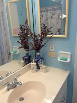 a bathroom sink with two blue vases and a mirror at Flats Hospitality in Plantation