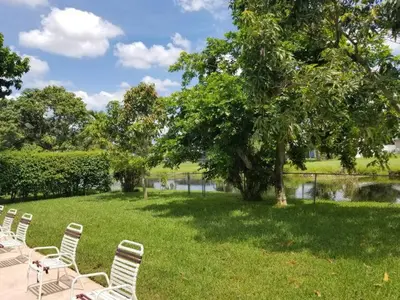 a row of chairs sitting in the grass near a tree at Flats Hospitality in Plantation