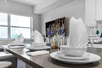 a dining room table with white plates and wine glasses at Sunny 1BR Unit With Free Parking Prime Location in Miami