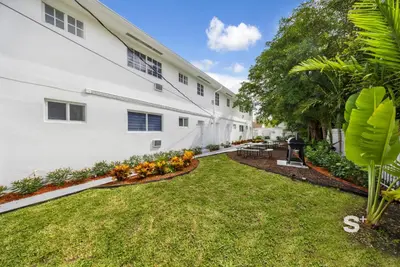 a courtyard of a white building with a yard at Stylish Studio - Parking & Gym Near Aventura in Miami
