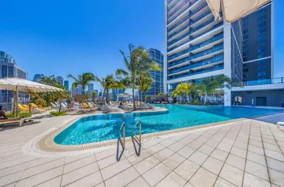 a swimming pool with palm trees and a tall building at Skyline 1-BD Condo - City & Ocean View in Miami