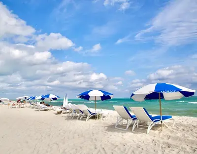 a group of chairs and umbrellas on a beach at Miami2 Beach Stay 3 min to Ocean in Miami Beach