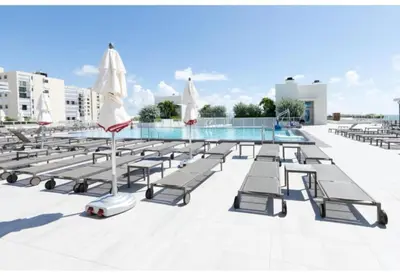 a row of chaise lounge chairs next to a swimming pool at Splendid apartment for 4 pax partial view of the beach in Hollywood M in Hollywood