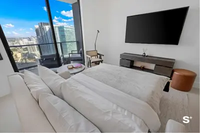 a bedroom with a large white bed and a flat screen tv at Luxury 1-BD with Breathtaking Downtown Views in Miami