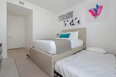 a white bedroom with two beds and a doorway at Miami Escape Views & Amenities in Hollywood