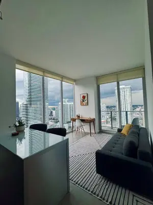 a living room with a couch and a table and windows at Elevated Elegance Luxe View Pool Free Parking in Miami