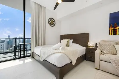 a bedroom with a bed and a balcony with a clock at Exclusive Studio with City Views in Downtown Miami in Miami
