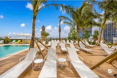 a row of white lounge chairs next to a pool at Modern Studio in Downtown Miami with Stunning City Views in Miami