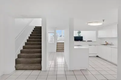 a white kitchen with a staircase with white cabinets at Shine Suites Balcony Duplex 9 in Miami Beach