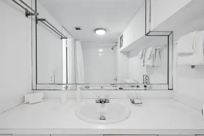 a white bathroom with a sink and a mirror at Shine Suites Balcony Duplex 9 in Miami Beach