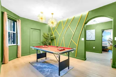 a ping pong table in a room with green walls at Luxury Glow Villa Miami - 4K Private Cinema, Heated Pool & Spa, Game Room - 5BR Lakefront Estate for 12 Guests in Hammocks