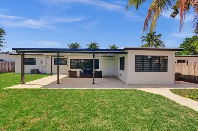 a white house with a patio and grass at Luxe Haven Near Aventura in Ives Estates