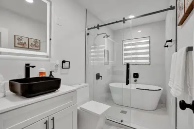a white bathroom with a black sink and a tub at Luxe Haven Near Aventura in Ives Estates