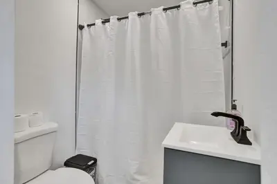 a white bathroom with a shower curtain and a toilet at Serene Suite Near Aventura in Ives Estates