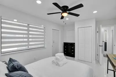 a white bedroom with a ceiling fan and a bed at Serene Suite Near Aventura in Ives Estates